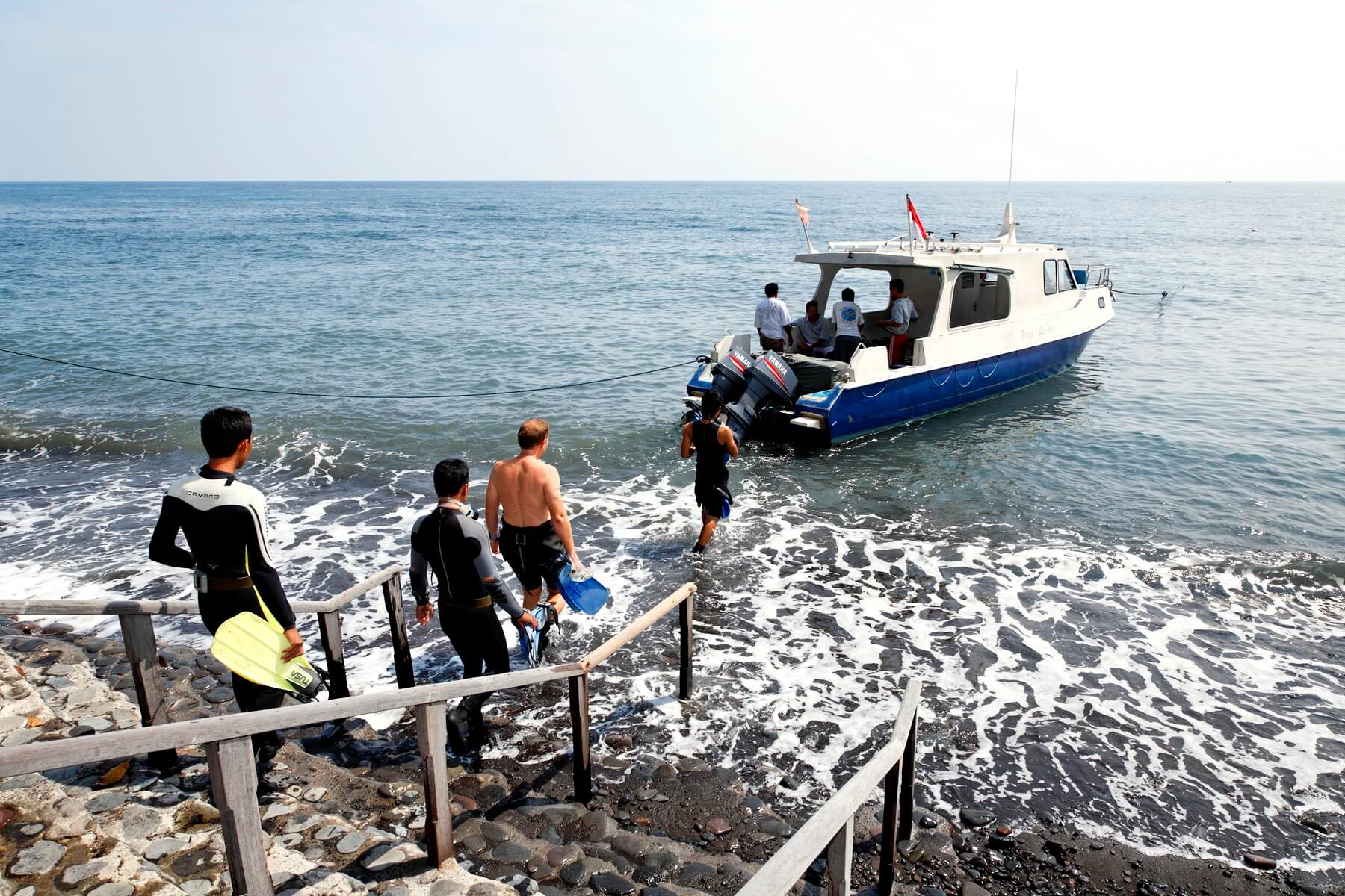 Urlauber brechen mit einem Tauchboot zu einem Tauchausflug in den Gewässern nahe des Alam Anda Ocean Front Resort & Spa auf.