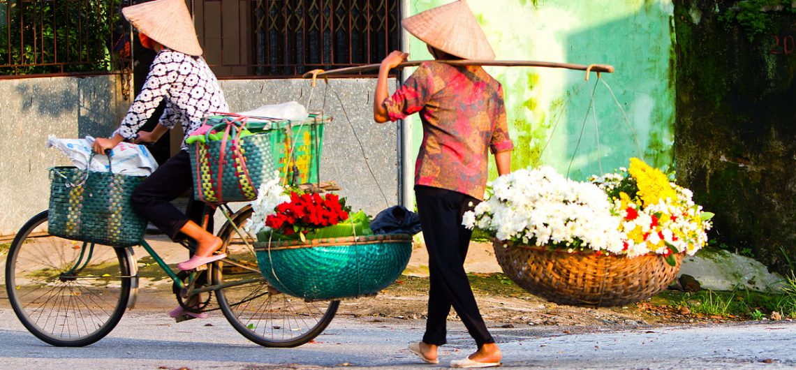 Blumenverkäuferinnen durchstreifen die Straßen im vietnamesischen Hanoi